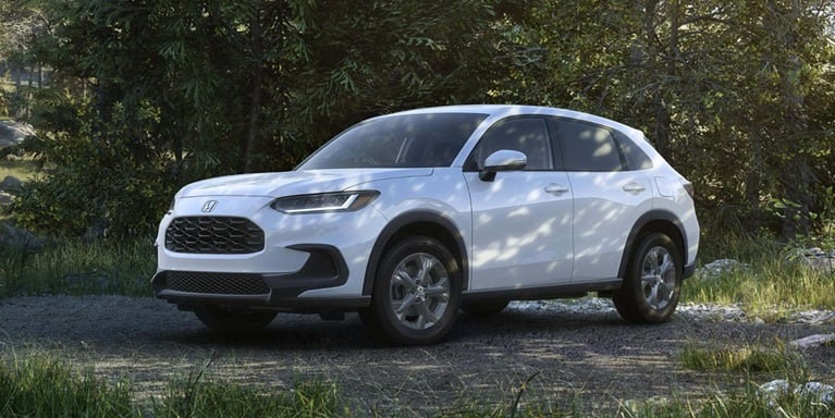2027 Honda HR-V LX in Platinum White Pearl front view parked on a dirt path in a forest (Subcompact Crossover SUV).