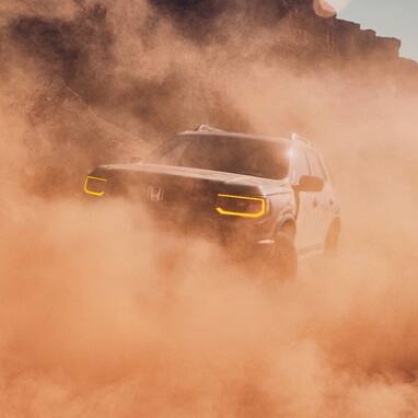2027 Honda Passport TrailSport Elite in Ash Green Metallic front driving through a dust cloud in the desert (Mid-Size SUV).